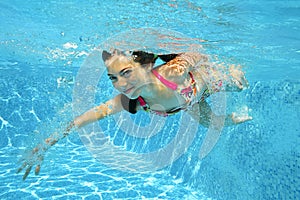 Child swims in pool underwater, happy active girl dives and has fun under water, kid sport