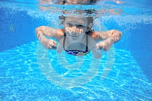 Child swims in pool underwater, happy active girl has fun