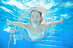 Child swims in pool underwater, happy active girl has fun under water, kid sport