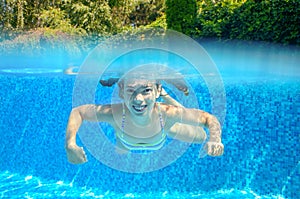 Child swims in pool underwater, happy active girl has fun under water, kid sport