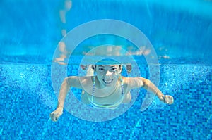 Child swims in pool underwater, happy active girl has fun under water, kid sport