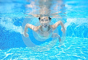 Child swims in pool underwater, happy active girl has fun under water, kid sport