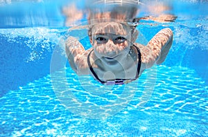 Child swims in pool underwater, happy active girl has fun under water, kid sport