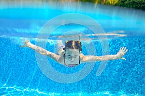 Child swims in pool underwater, happy active girl has fun under water, kid sport