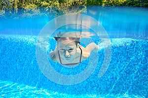 Child swims in pool underwater, happy active girl has fun under water, kid sport