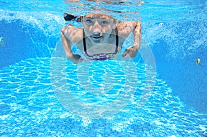 Child swims in pool underwater, happy active girl has fun under water, kid sport