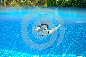 Child swims in pool underwater, happy active girl has fun under water, kid sport