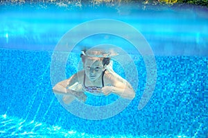 Child swims in pool underwater, happy active girl has fun under water, kid sport