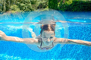 Child swims in pool underwater, happy active girl has fun under water, kid sport