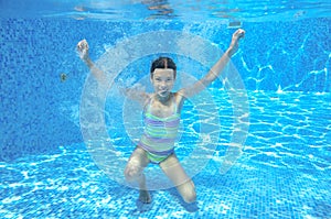 Child swims in pool underwater, happy active girl has fun under water, kid sport