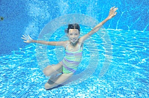 Child swims in pool underwater, happy active girl has fun under water, kid sport