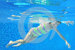 Child swims in pool underwater, happy active girl has fun under water, kid sport