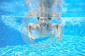 Child swims in pool underwater, happy active girl has fun under water, kid sport