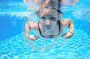 Child swims in pool underwater, happy active girl has fun under water, kid sport