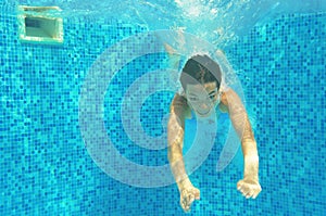 Child swims in pool underwater, happy active girl jumps, dives and has fun, kid sport