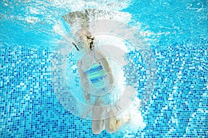 Child swims in pool underwater, happy active girl jumps, dives and has fun under water, kids fitness and sport