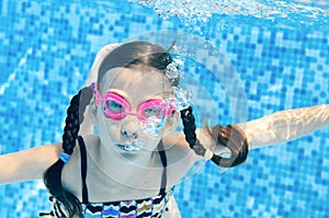 Child swims in swimming pool underwater, happy active girl dives and has fun under water, kid sport on family vacation photo