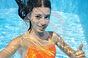 Child swims in swimming pool underwater, happy active teenager girl dives and has fun under water, kid fitness and sport