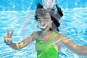 Child swims in swimming pool underwater, happy active teenager girl dives and has fun under water, kid fitness and sport