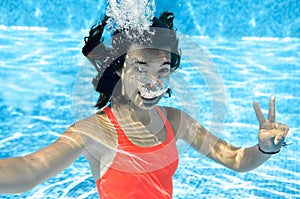 Child swims in swimming pool underwater, happy active teenager girl dives and has fun under water, kid fitness and sport