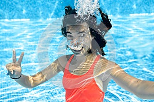 Child swims in swimming pool underwater, happy active teenager girl dives and has fun under water, kid fitness and sport