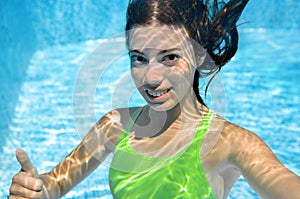 Child swims in swimming pool underwater, happy active teenager girl dives and has fun under water, kid fitness and sport