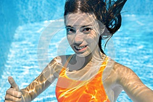 Child swims in swimming pool underwater, happy active teenager girl dives and has fun under water, kid fitness and sport photo