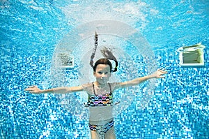 Child swims in swimming pool underwater, little active girl jumps, dives and has fun under water, kids fitness and sport
