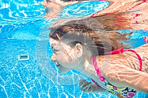 Child swims underwater in swimming pool, active girl dives and has fun under water, kid sport on family vacation