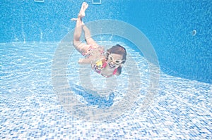 Child swims underwater in swimming pool, active little girl dives and has fun under water, kid fitness and sport