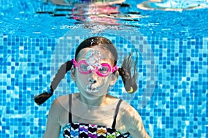 Child swims underwater in swimming pool, funny little girl dives and has fun under water, kid making bubbles