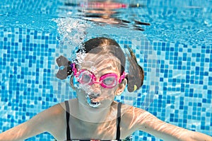 Child swims underwater in swimming pool, funny little girl dives and has fun under water, kid making bubbles