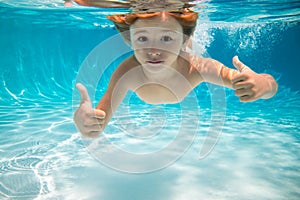 Child swims underwater in swimming pool, happy active boy dives and has fun under water, kids watersport. Children play