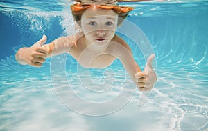 Child swims underwater in swimming pool, happy active boy dives and has fun under water, kids watersport. Children play