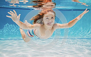 Child swims underwater in swimming pool, happy active boy dives and has fun under water, kids watersport. Summer