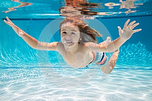 Child swims underwater in swimming pool, happy active boy dives and has fun under water, kids watersport. Summer