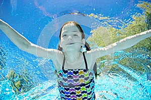 Child swims underwater in swimming pool, happy active teenager girl dives and has fun under water, kid fitness and sport