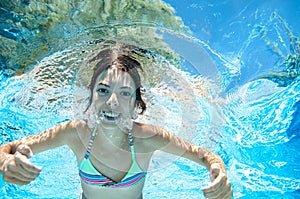 Child swims underwater in swimming pool, happy active teenager girl dives and has fun under water, kid fitness and sport