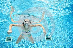 Child swims underwater in swimming pool, happy active teenager girl dives and has fun under water, kid fitness and sport