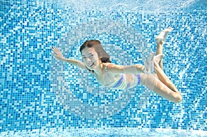 Child swims underwater in swimming pool, happy active teenager girl dives and has fun under water, kid fitness and sport