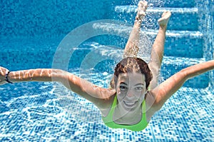 Child swims underwater in swimming pool, happy active teenager girl dives and has fun under water, kid fitness and sport