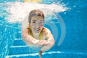 Child swims underwater in swimming pool, happy active teenager girl dives and has fun under water, kid fitness and sport