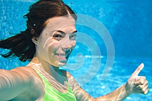 Child swims underwater in swimming pool, happy active teenager girl dives and has fun under water, kid fitness and sport