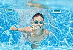 Child swims underwater in swimming pool, happy active teenager girl dives and has fun under water, kid fitness and sport