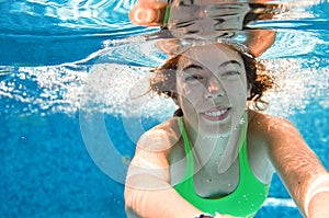 Child swims underwater in swimming pool, happy active teenager girl dives and has fun under water, kid fitness and sport