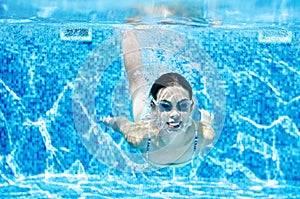 Child swims underwater in swimming pool, happy active teenager girl dives and has fun under water, kid fitness and sport photo