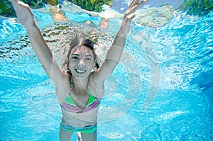 Child swims underwater in swimming pool, happy active teenager girl dives and has fun under water, kid fitness and sport