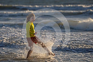 Child in swimwear running into sea water during summer holidays. Child running along ocean. Child on summer beach. Kid