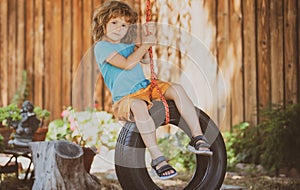 Child swing on backyard. Kid playing oudoor. Happy cute little boy swinging and having fun healthy summer vacation