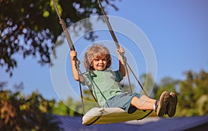 Child swing on backyard. Kid playing oudoor. Happy cute little boy swinging and having fun healthy summer vacation